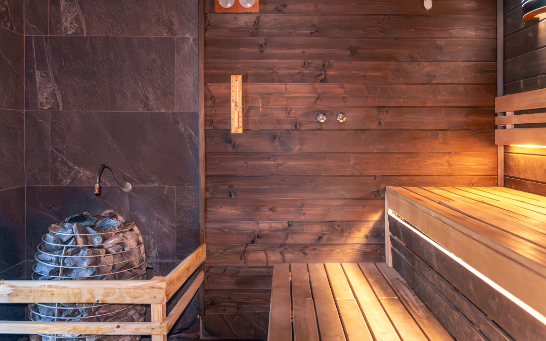 Wooden sauna interior with heated stones and bench used for heat therapy and recovery
