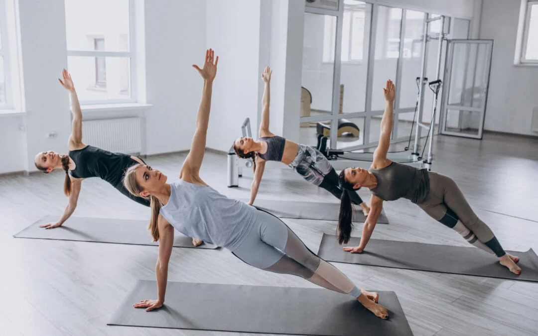 Group of women performing side plank exercises together in a fitness studio