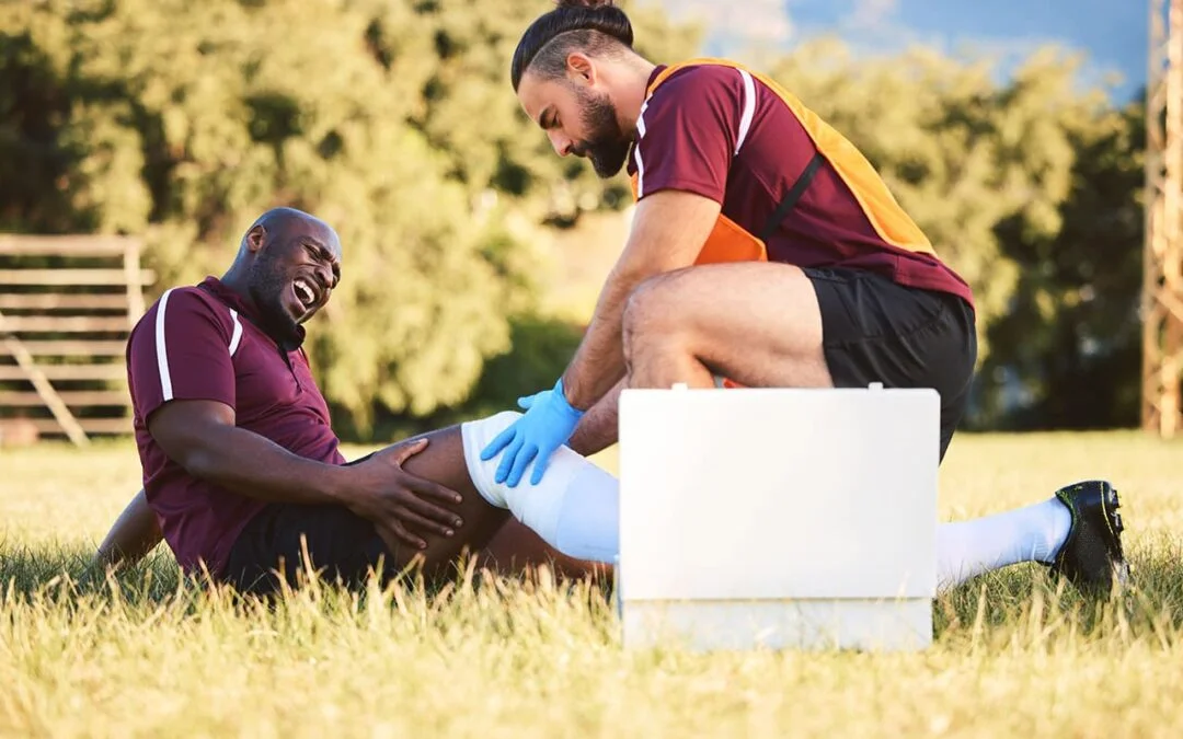 Male athlete receiving on-field medical assistance for a painful knee injury